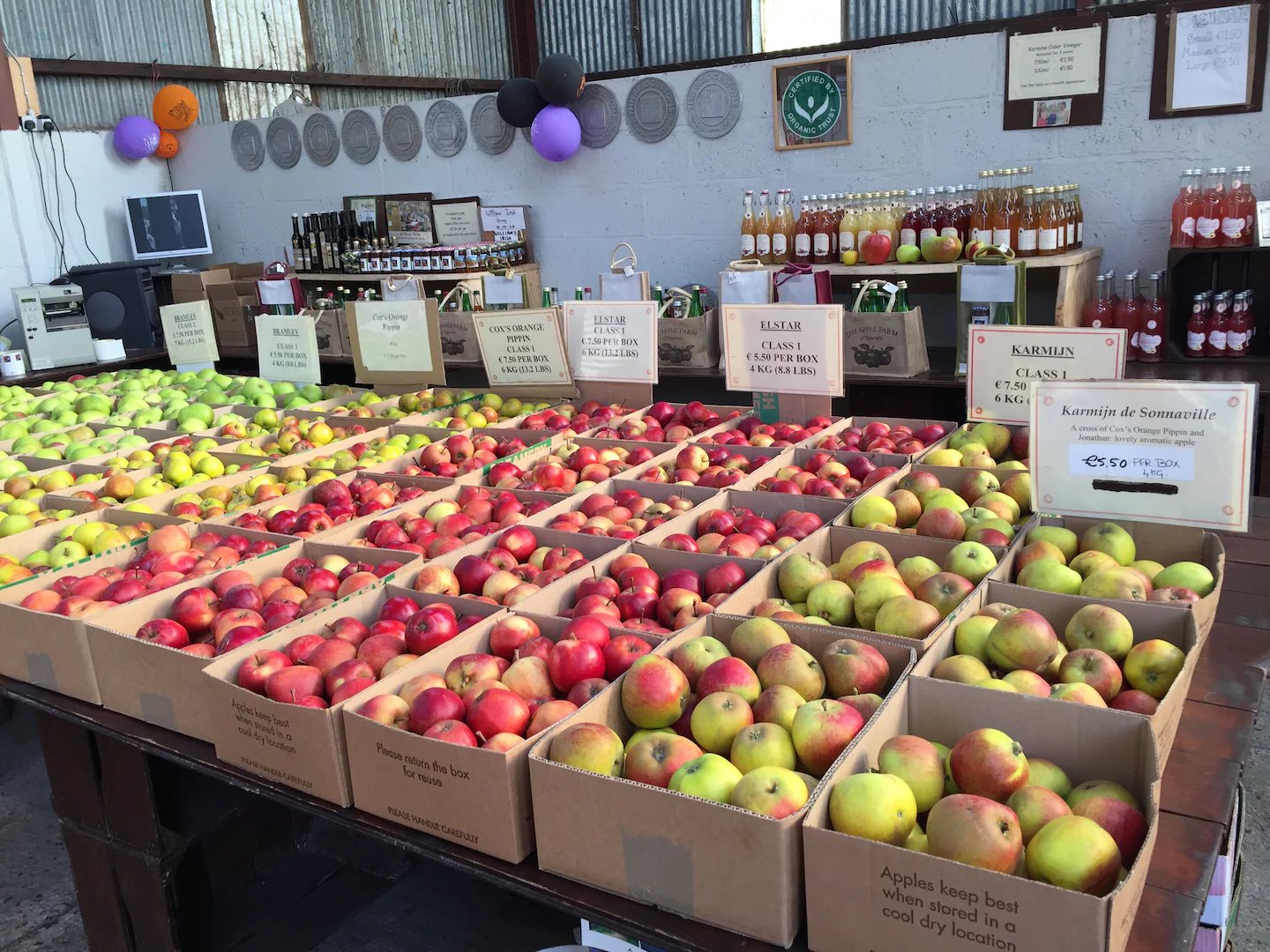 Boxes of apples for sale in the farm shop, with our juices on the shelves behind